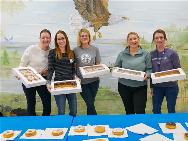 five women with boxes of donuts